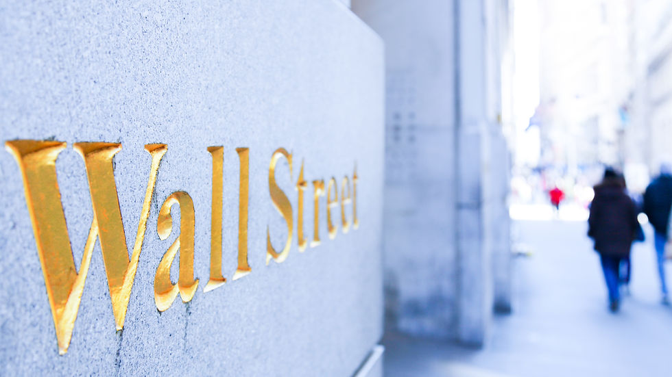 Large gold letters are engraved on a grey wall. The Text WALL STREET appears in bold gold letters.